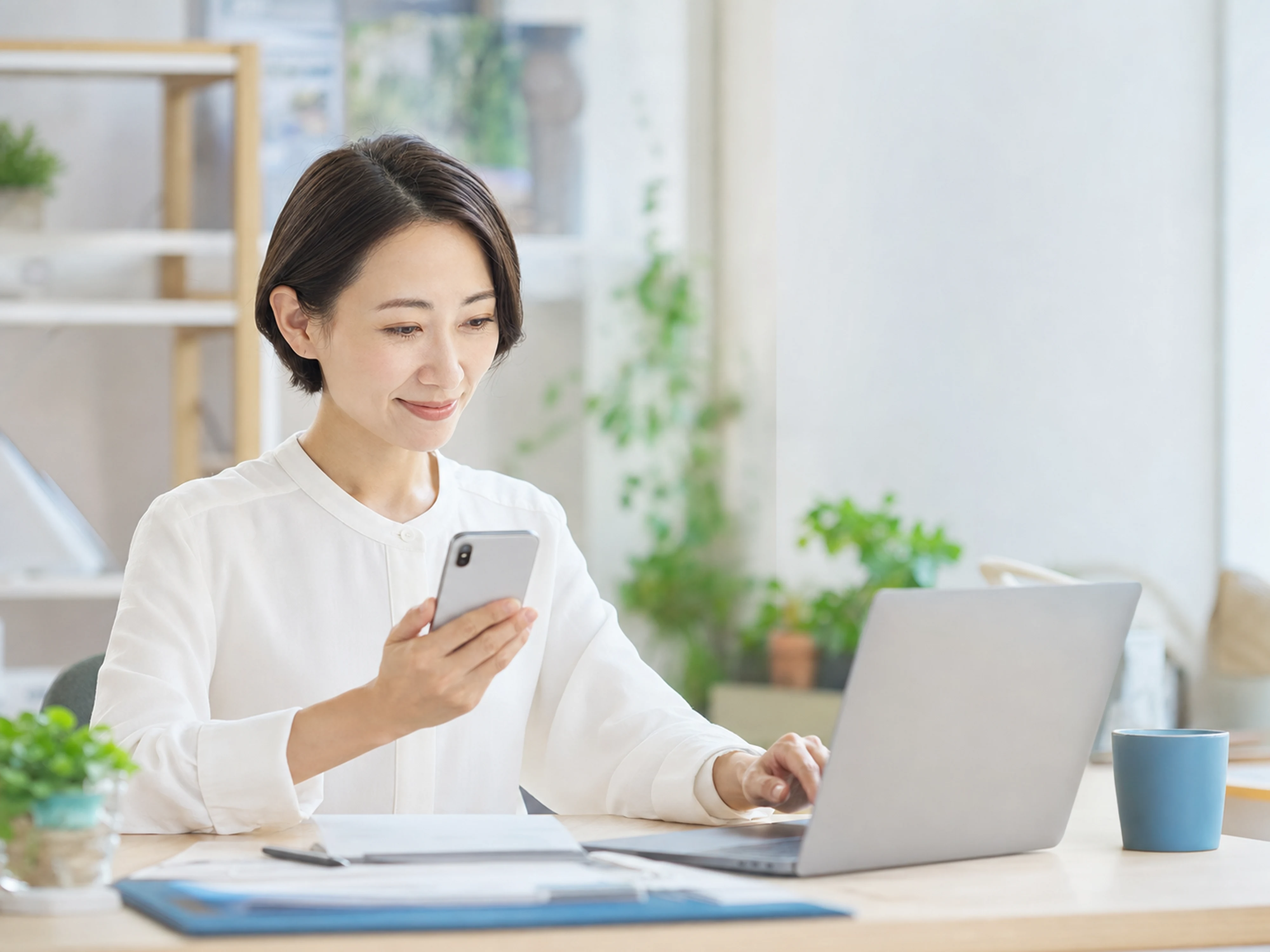 事業者がスマートフォンとノートパソコンを使ってお客様の問い合わせへ対応する様子